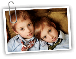 Two young boy twins wearing ties looking up at the camera