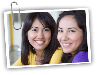 Young adult twin girls with dark hair both looking at the camera and smiling