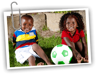 Boy/girl African American twin pair sitting the grass with a soccer ball between them