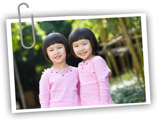 Young Asian twin girls looking at the camera and smiling