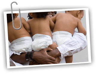 Close up of an adult holding three babies in diapers
